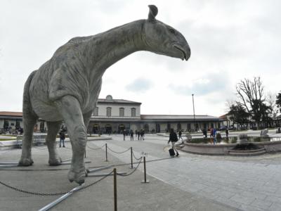 Sconvolgente ritrovamento in una piazza: un uomo morto dentro alla zampa di un dinosauro di cartapesta