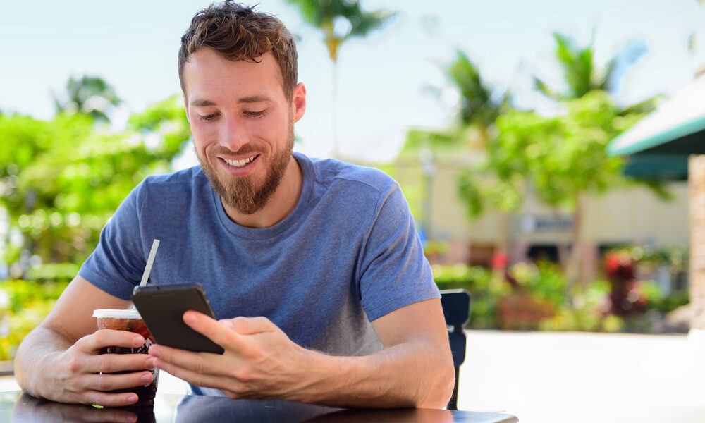 Uomo con smartphone al tavolino di un bar