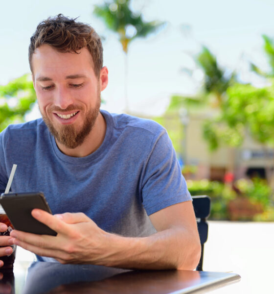 Uomo con smartphone al tavolino di un bar